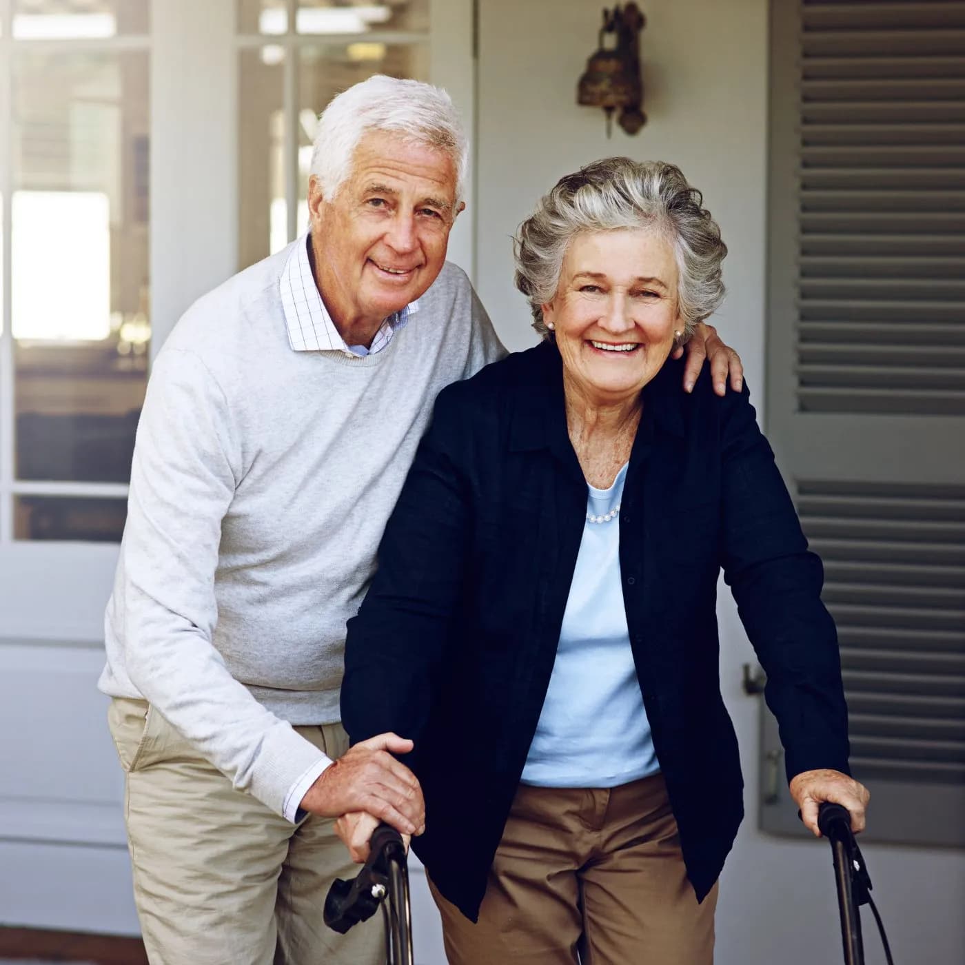 Senior couple smiling outside their home